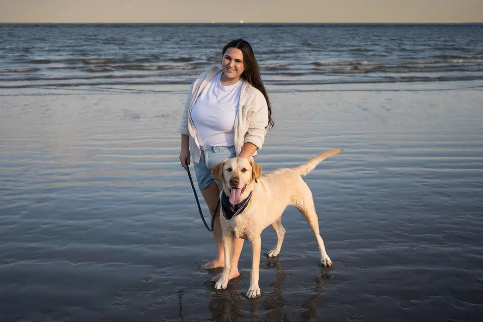 زنی که در ساحل ایستاده و قلاده‌ سگ را در دست دارد