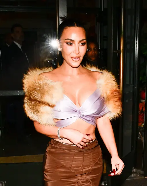 کیم کارداشیان در لباس شیک: ژاکت مویی، تاپ ابریشمی پیچیده، دامن با کمر بلند، با اطمینان قدم می‌زند و به‌سوی جلو نگاه می‌کند