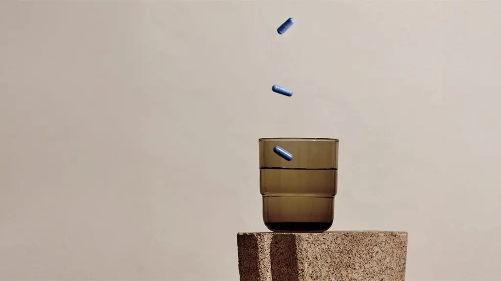 قرص‌های ضدکلسترول که از بالا به داخل یک لیوان می‌افتند