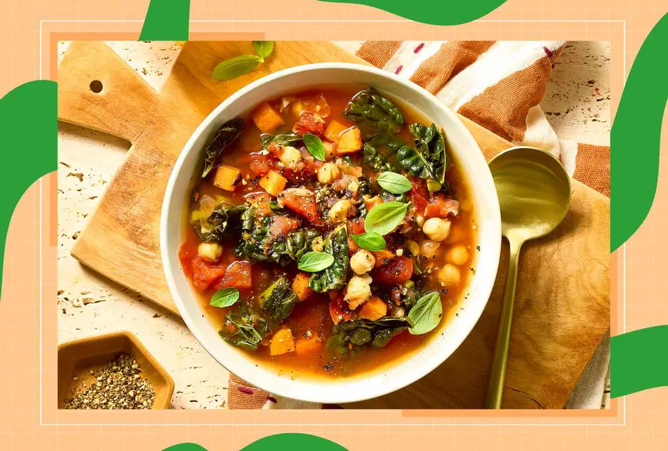 یک کاسه خورشت با سبزیجات و گیاهان معطر بر روی تختهٔ چوبی به‌همراه یک قاشق