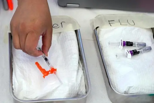 فایل – واکسن کووید، در سمت چپ آماده شده است، در حالی که واکسن آنفولانزا در کنارش در مرکز منابع جامعه L.A. Care و Blue Shield of California Promise Health Plans قرار دارد؛ جایی که به اعضا و عموم واکسنهای رایگان آنفولانزا و کووید‑۱۹ ارائه میدادند، ۲۸ اکتبر ۲۰۲۲، در لینوود، کالیفرنیا (عکس AP/مارک ج. ترل، فایل)